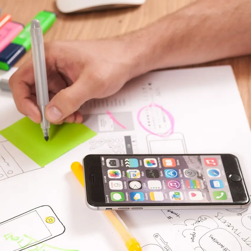 Software Entwicklung Iphone und eine Hand die UX für eine App zeichnet